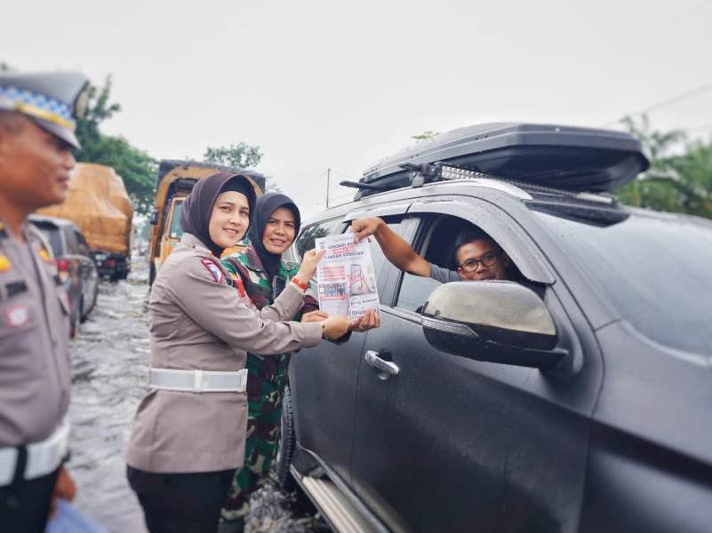 Bantu Pengemudi Lewati Banjir, Sinergitas TNI- Polri di Rohil Bagikan Brosur Pemilu Damai